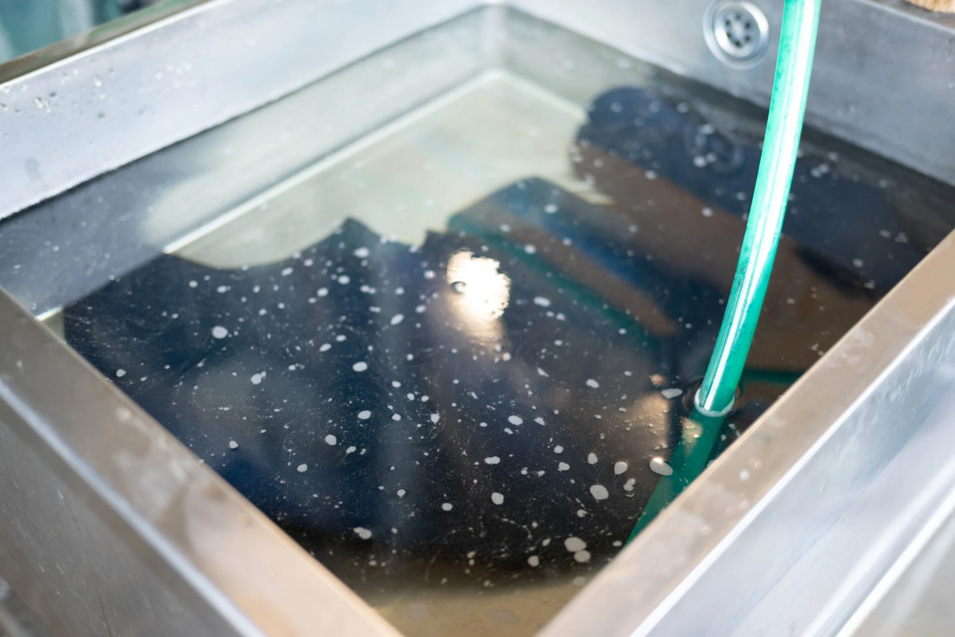 アルカリ性の藍染液に浸かっていた革を酸性の液に浸けて中和する